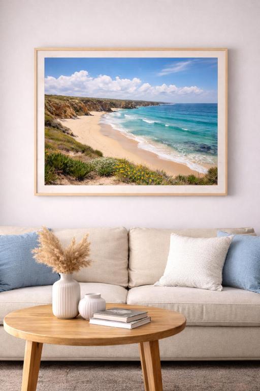 a living room with a couch and a picture of a beach at Blue House in Santiago do Cacém