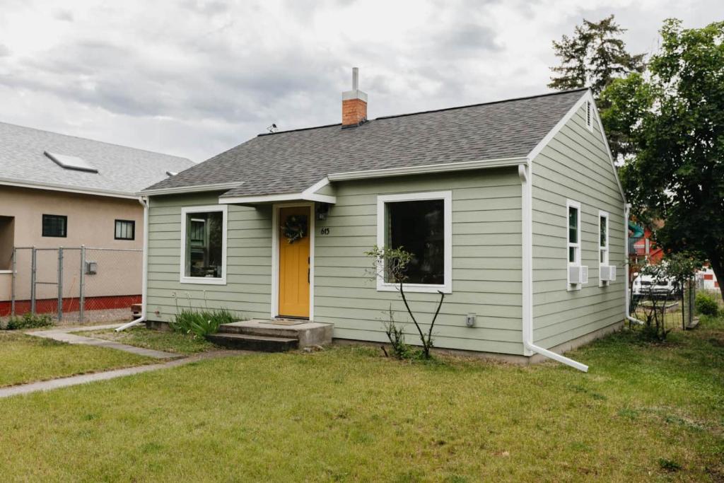 een klein wit huis met een gele deur bij Rose Park Cottage in Community Medical Center Heliport