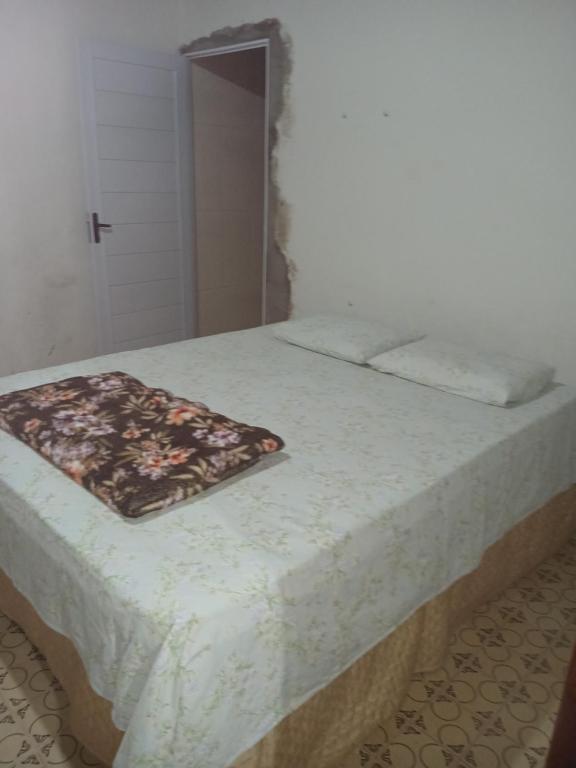 een wit bed met een bloemendeken erop bij Casa azul in Iguape