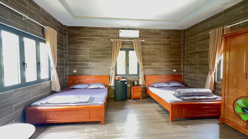 two beds in a room with two windows at Thiên Vy Homestay in Phu Quoc