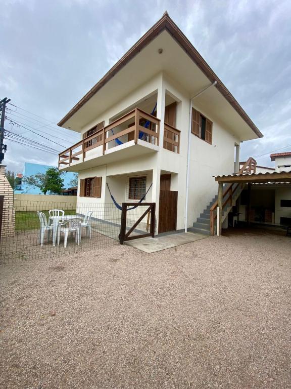 a white house with a balcony and a table at Casa aconchegante in Garopaba