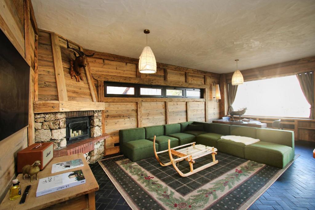 un soggiorno con divano verde e camino di Chalet Arpian Valmorel a Les Avanchers
