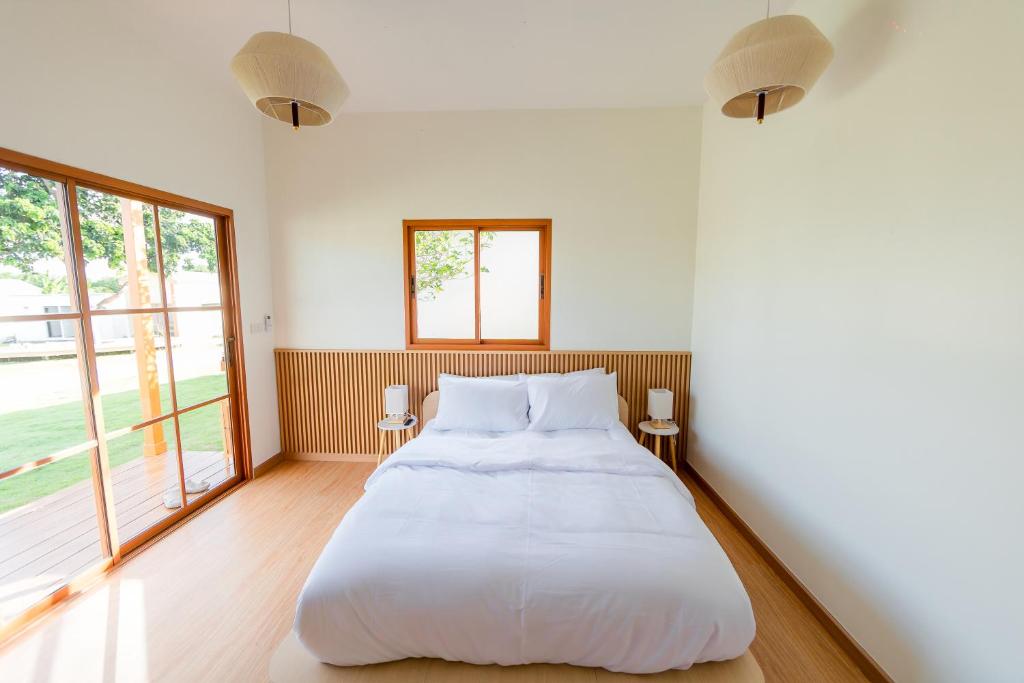ein weißes Schlafzimmer mit großem Bett und Fenstern in der Unterkunft Yugen House - Yuma in Nong Prue