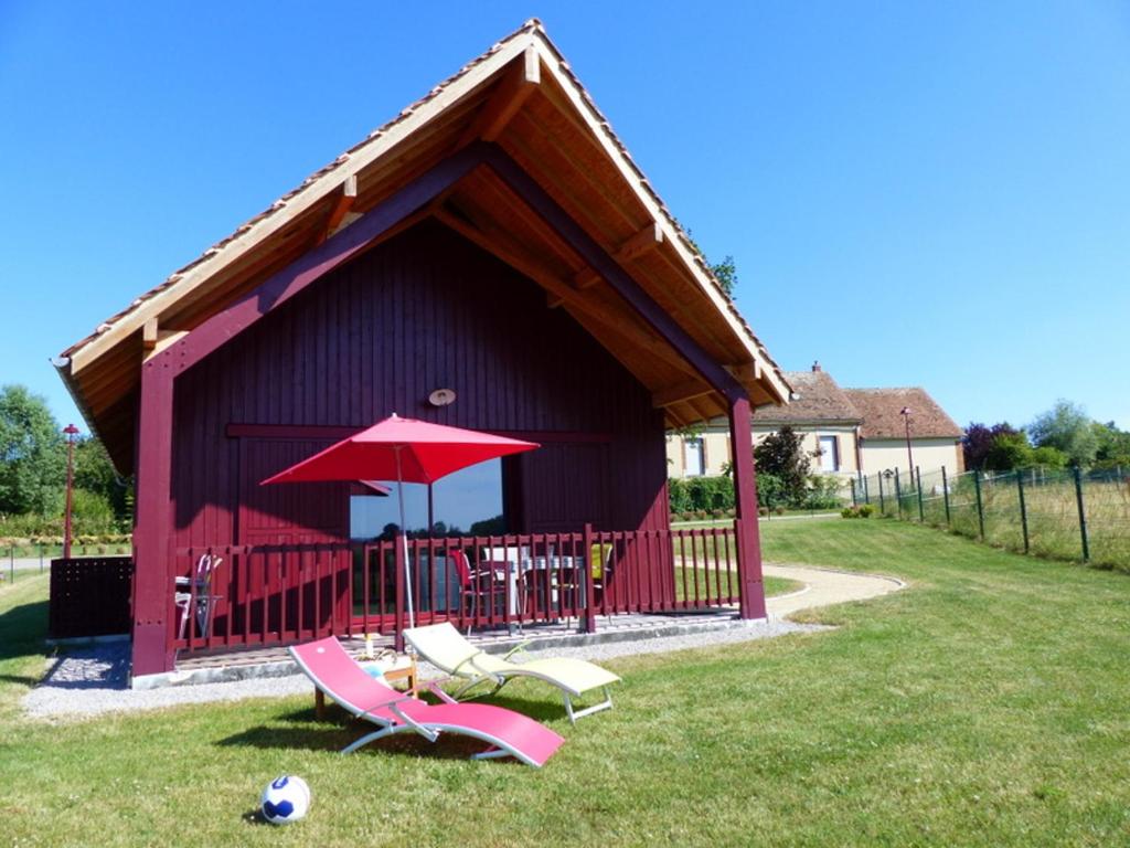 einem roten Schuppen mit Stühlen und einem roten Regenschirm in der Unterkunft Gîte familial dans le bocage Bourbonnais avec jardin privé - FR-1-489-93 in Meillard