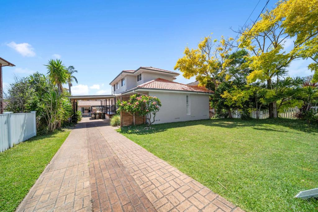 a house with a brick pathway in front of a yard at Karinya Jervis Bay - 4BR home & optional studio in Vincentia