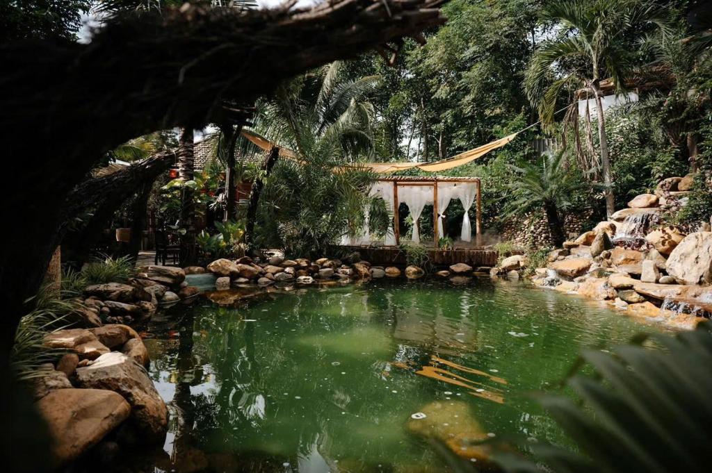 einen Teich in einem Garten mit einem Gebäude im Hintergrund in der Unterkunft LIA Retreat & Coffee 