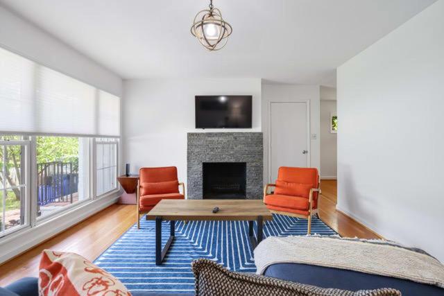 een woonkamer met oranje stoelen en een open haard bij Forest Glen Silver Spring Gem - Parking in Silver Spring