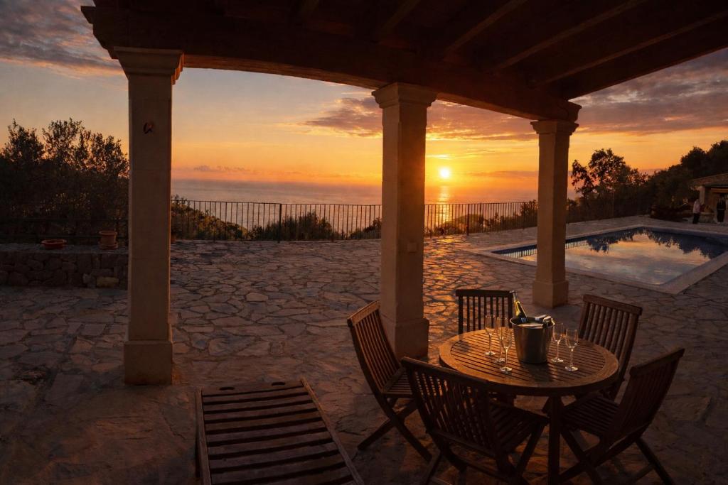 a table and chairs under a gazebo with the sunset at Cozy Chalet with Sea Views & Private Pool in Valldemossa