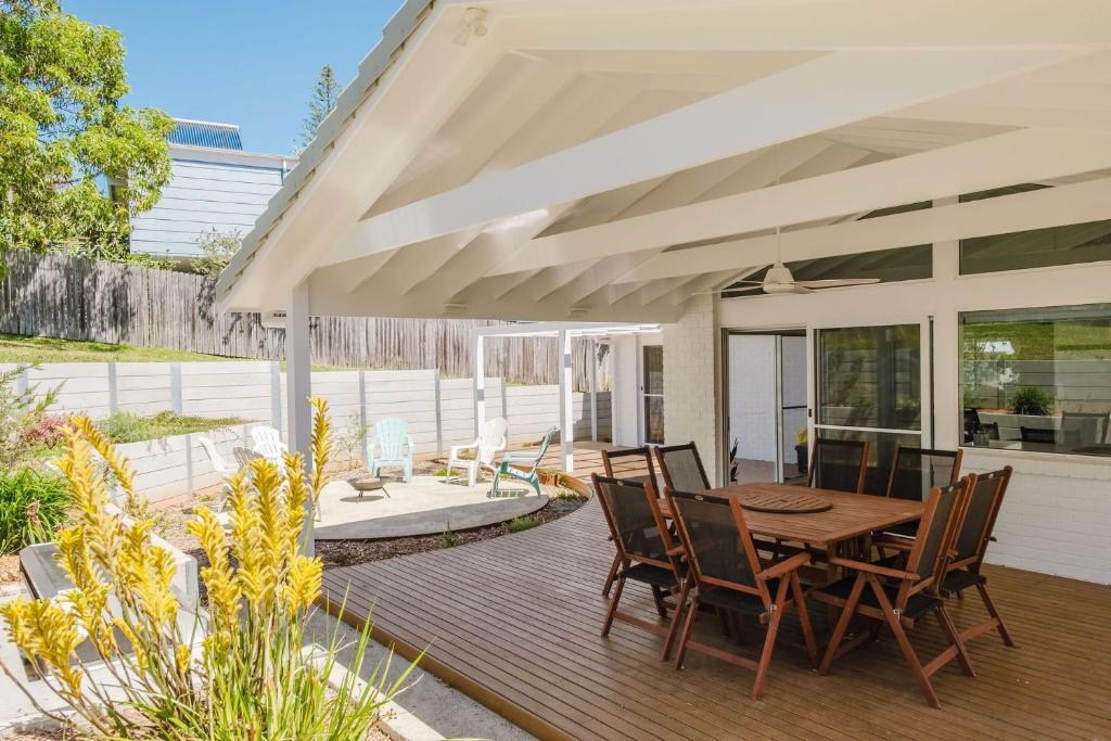 a patio with a wooden table and chairs at Ocean Haze - Putting Green, Firepit, Beach location in Mollymook