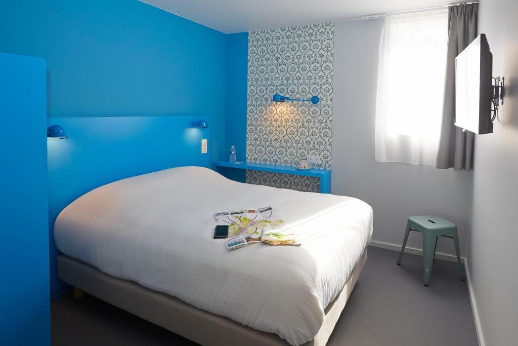 Un dormitorio azul con una cama con zapatos. en Coto Hotel en Beaune