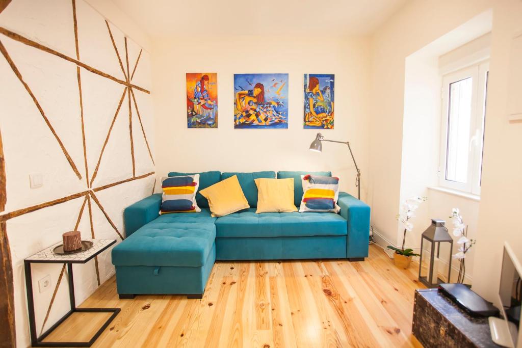 リスボンにあるGraça Traditional 2 bedroom apartmentのリビングルーム(青いソファ、絵画付)