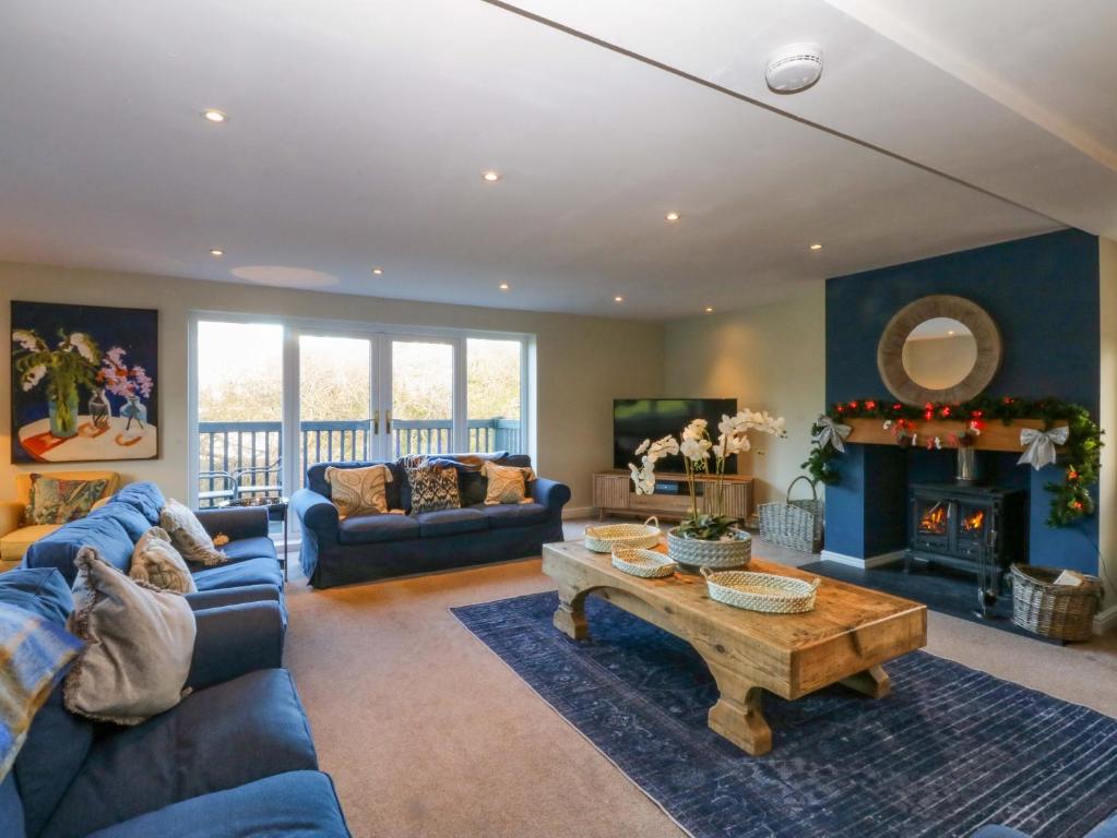 a living room with a blue couch and a table at Nant-yr-Rhedyn in Benllech