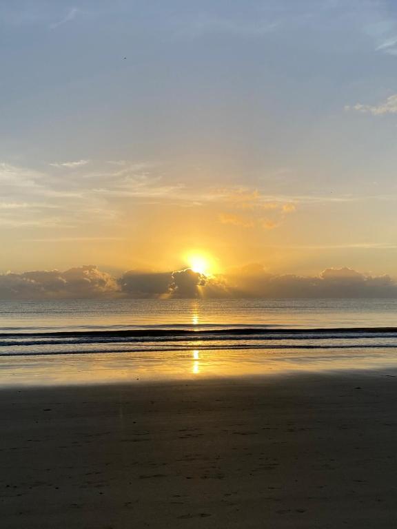 a sunset on the beach with the sun setting at Reefside Escape Silkari Resort in Port Douglas
