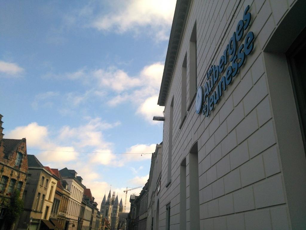 un bâtiment avec un panneau sur le côté d'une rue dans l'établissement Auberge de Jeunesse de Tournai, à Tournai