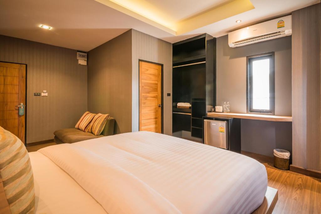 1 dormitorio con 1 cama blanca grande y 1 sofá en Le Terrarium Bed & Sleep Chiang Rai, en Chiang Rai