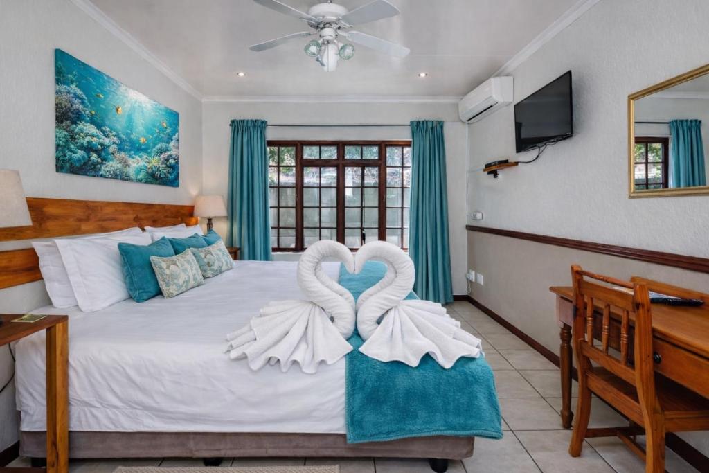 a bedroom with a bed with two swans in the middle at Lodge At The Link in Kempton Park