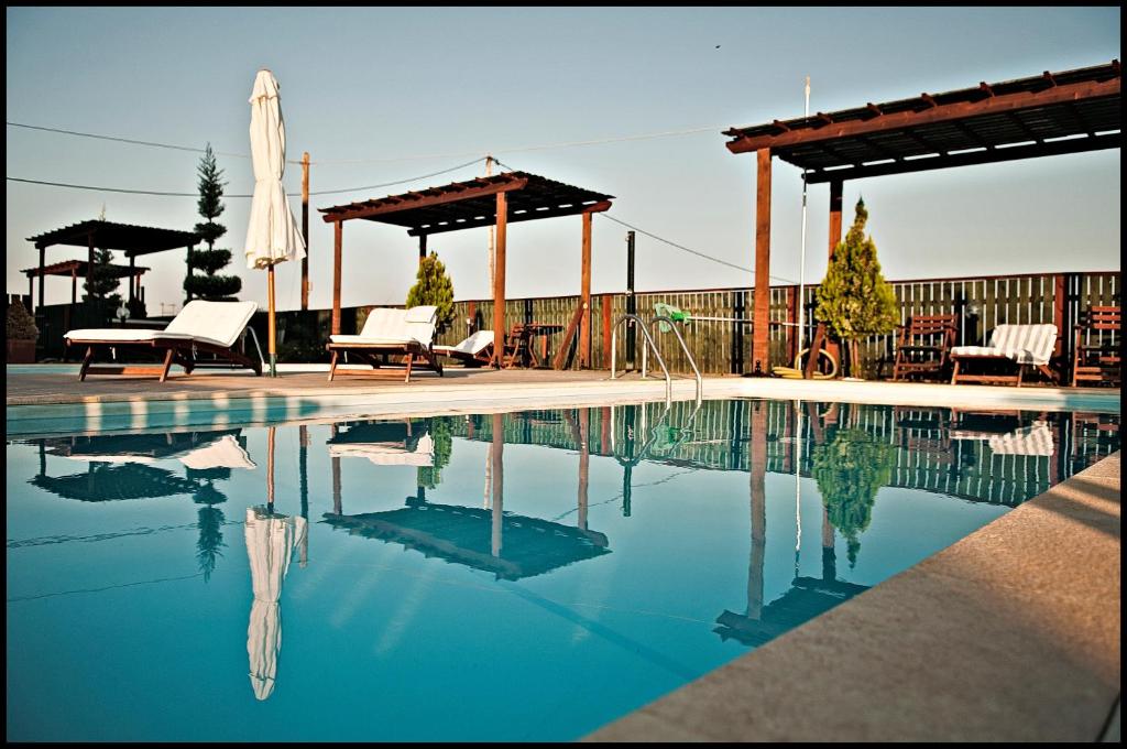a swimming pool with chairs and a gazebo at ilyda Residence apts in Skala Kallonis