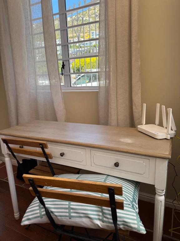a desk with a window and a telephone on it at Outspan Lodge in Fish Hoek