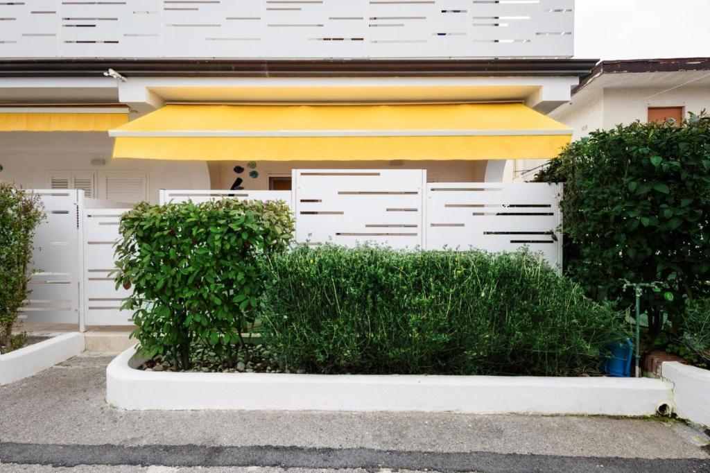 eine Hecke vor einem Haus mit einem gelben Regenschirm in der Unterkunft VENART by AnrealeRooms in Paestum