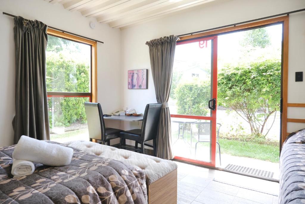 a bedroom with a bed and a table and a window at Forest Trail Lodge in Hanmer Springs