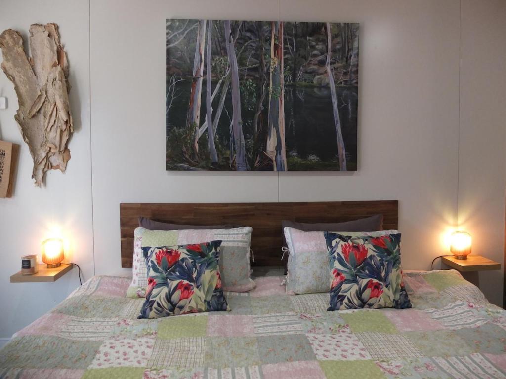 a bedroom with a bed with pillows and two lamps at Little Birdy in Tawonga