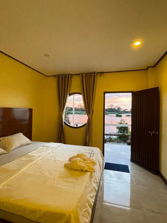 une chambre avec un lit et une grande fenêtre dans l'établissement Tena Guest House, à Don Det