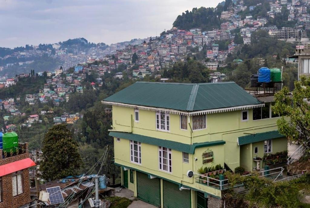 a yellow house with a green roof on a mountain at Aashray kunj homestay in Jāmb