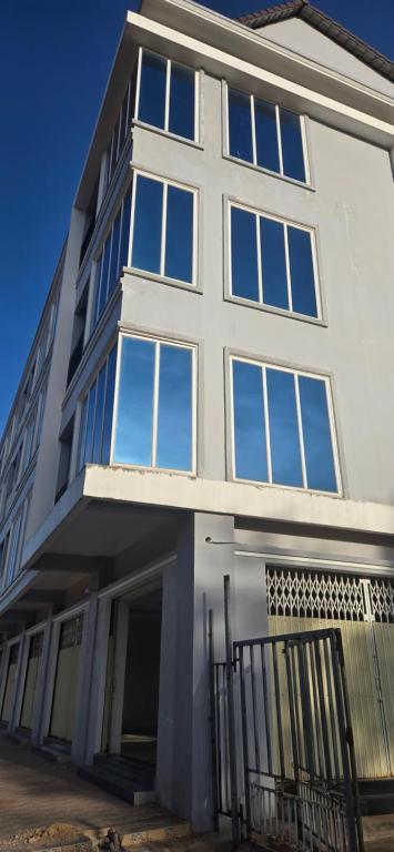 a white building with a lot of windows at SAMBATH SAKSETH Guesthouse in Phumĭ Nésat