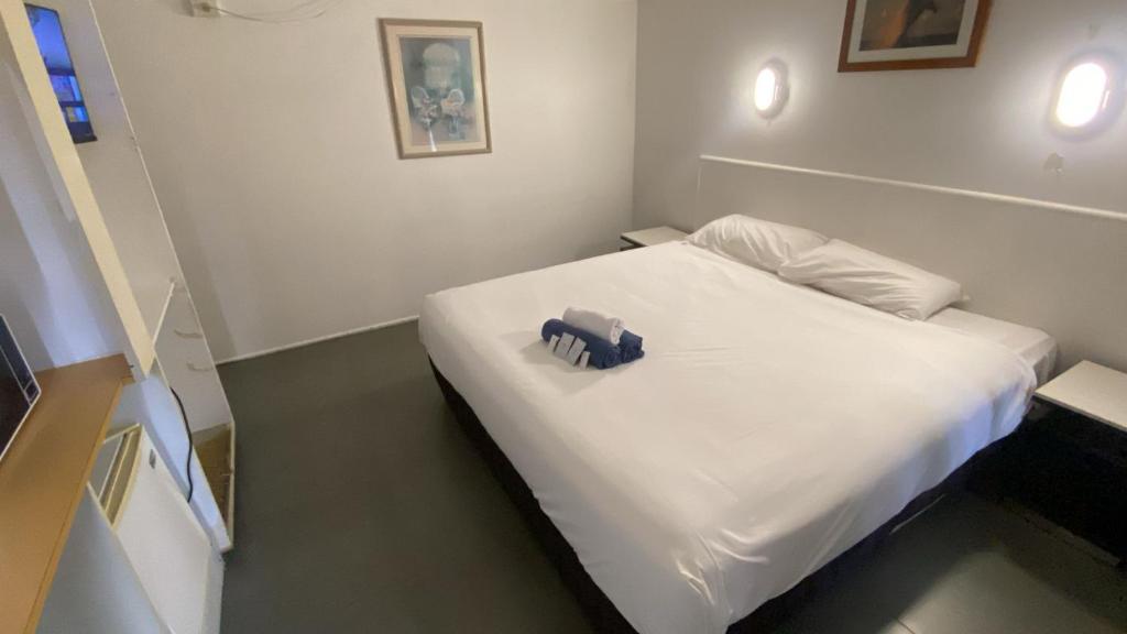 ein weißes Bett mit einem blauen Gegenstand darauf in der Unterkunft Mayfield Motel in Mayfield