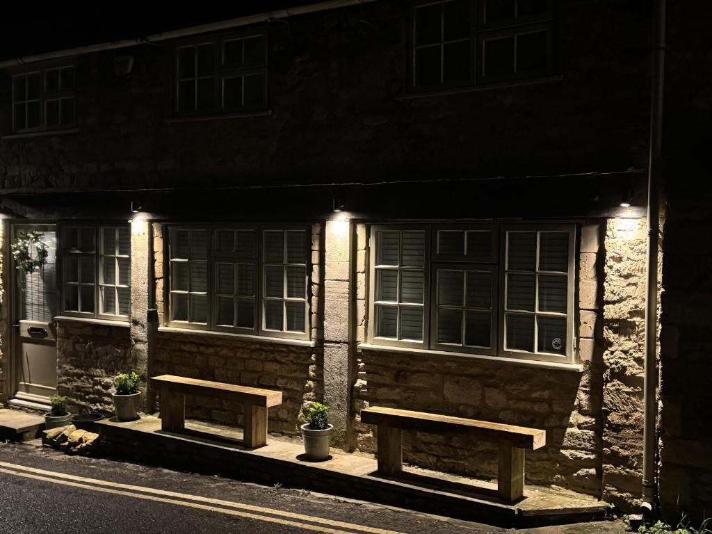 twee banken voor een gebouw 's nachts bij Priory Weavers Cottage in Burford