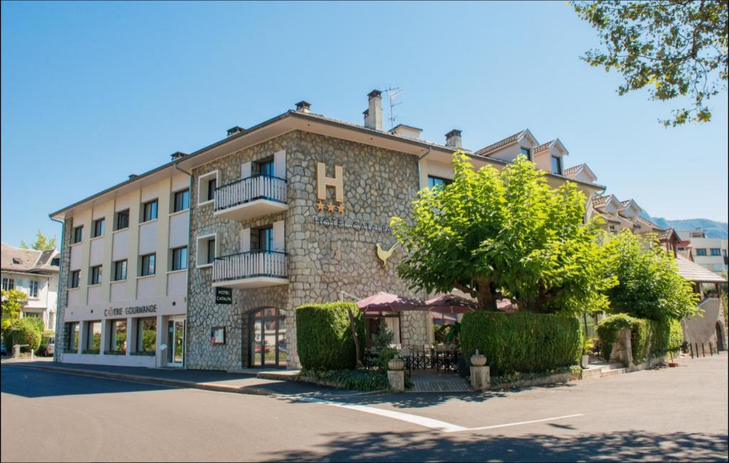 un gran edificio de piedra con un árbol delante de él en Hôtel Catalpa, en Annecy