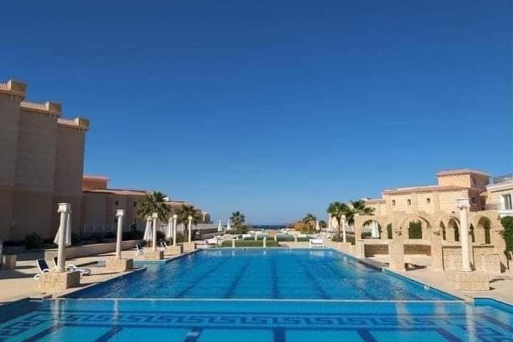 ein großer Swimmingpool mit Palmen und Gebäuden in der Unterkunft Alaydin in Hurghada