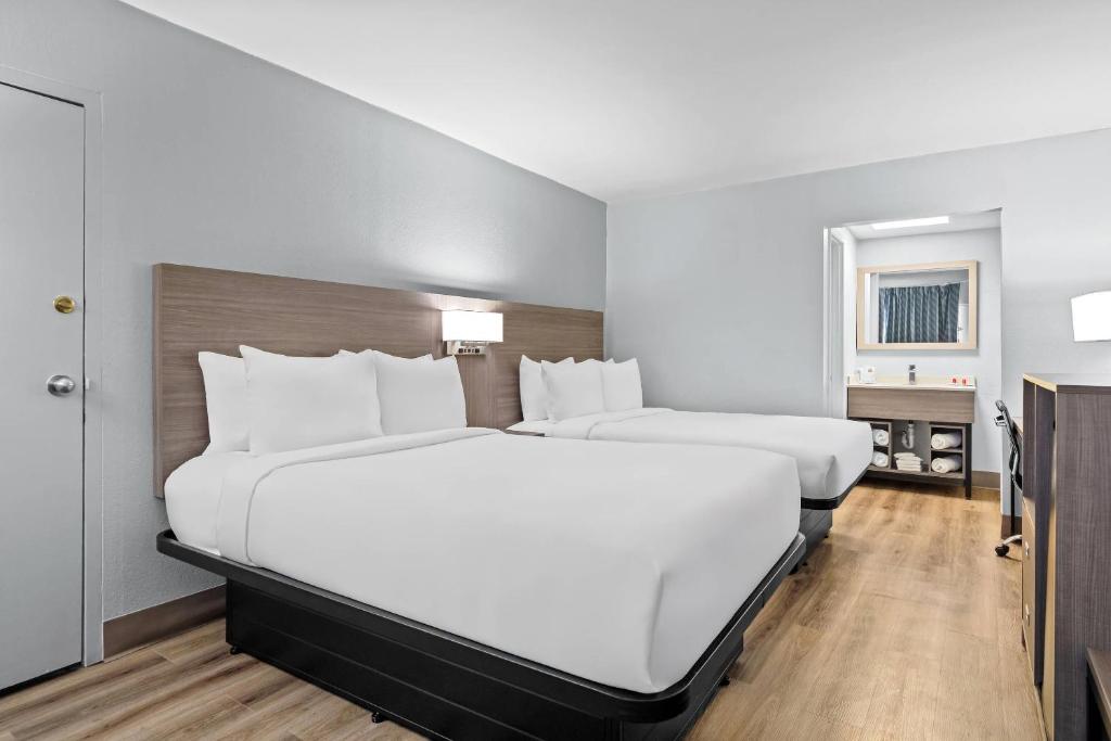 two beds in a hotel room with white pillows at Econo Lodge Daytona Beach - Speedway in Daytona Beach