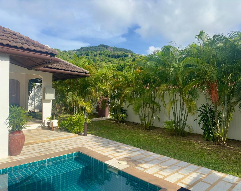 a swimming pool in front of a house with palm trees at Bamboo Villa in Ko Tao