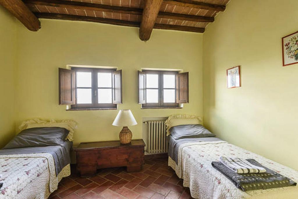 two beds in a room with two windows at Relax Palazzo Monaci in Asciano