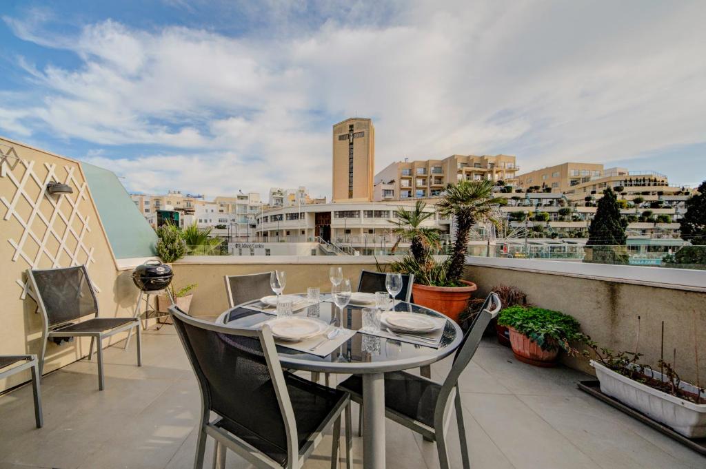 a table and chairs on a balcony with a view of a city at St Julian's 2Br Apartment with Private Jacuzzi in St. Julianʼs