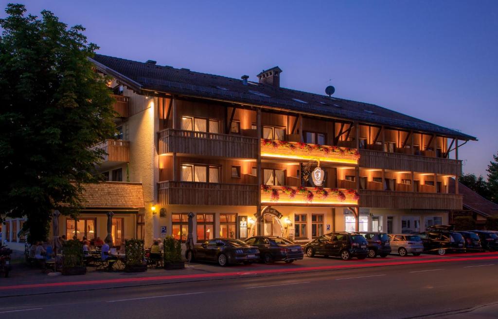 un gran edificio con coches estacionados frente a él en Landgasthof Zur Post, en Schwangau