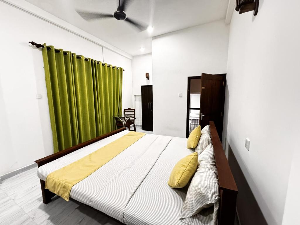 een slaapkamer met een bed met een groen gordijn bij Hagiazo Guest Inn Mirissa in Mirissa