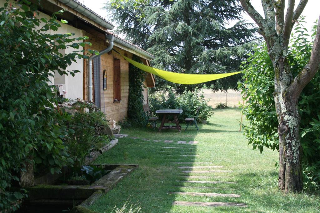Una hamaca amarilla colgando de un árbol al lado de una casa. en Gite Vercors-Chambaran, en Saint-Marcellin
