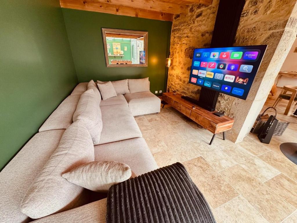een woonkamer met een grote bank en een flatscreen-tv bij Gîte de Marcenac in Lalbenque