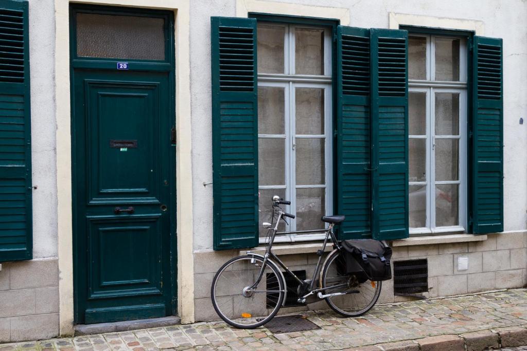 uma bicicleta estacionada em frente a um edifício com persianas verdes em Wazemoff em Lille