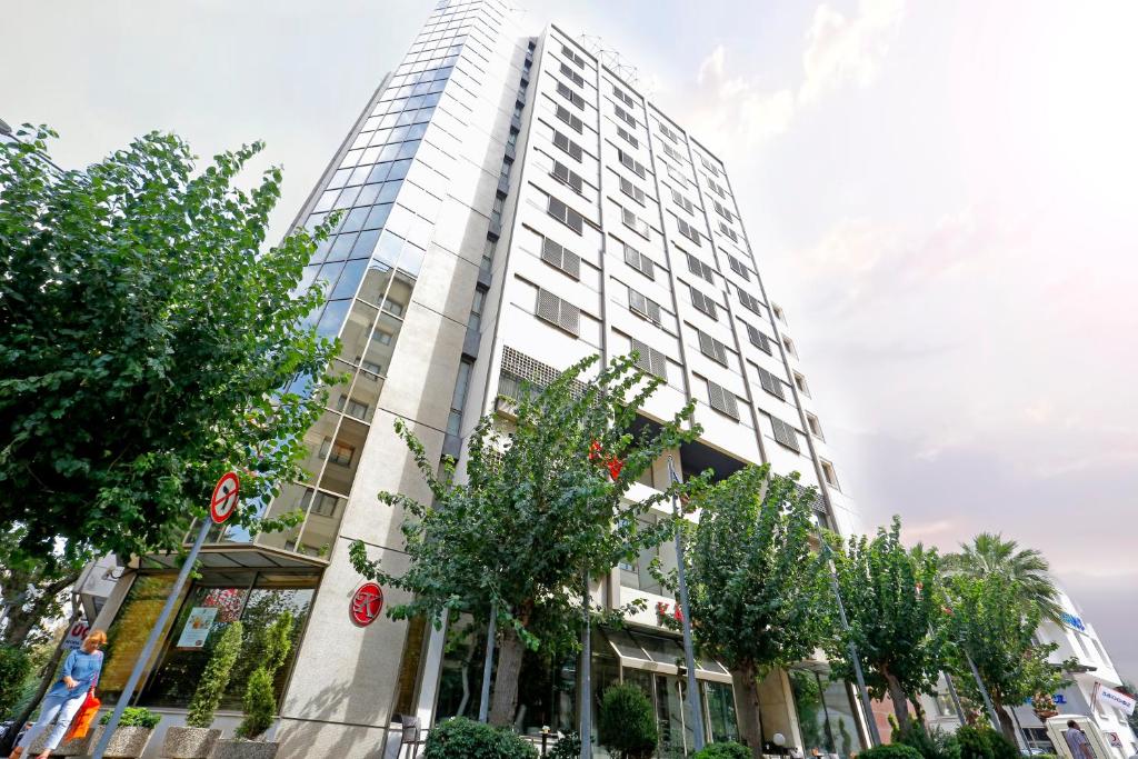 een hoog gebouw met bomen ervoor bij Kaya Prestige Oteli in Izmir