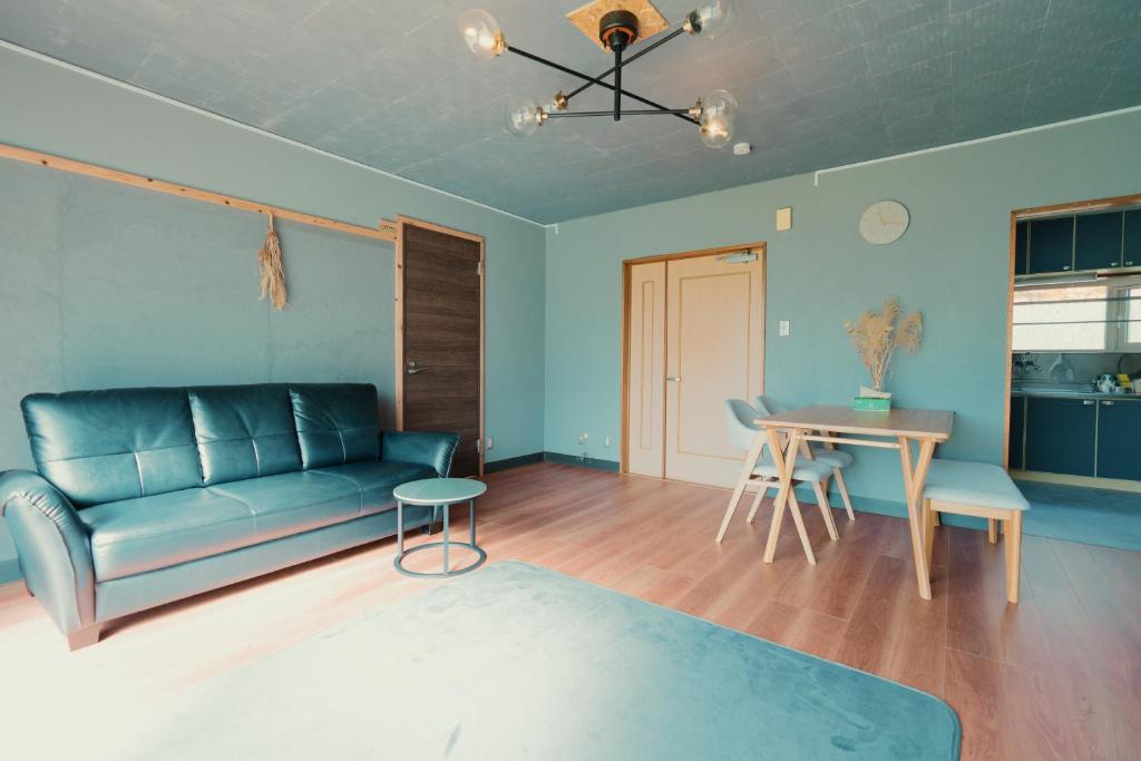 a living room with a blue couch and a table at ペコレラ学舎 Teacher House in Yakumo