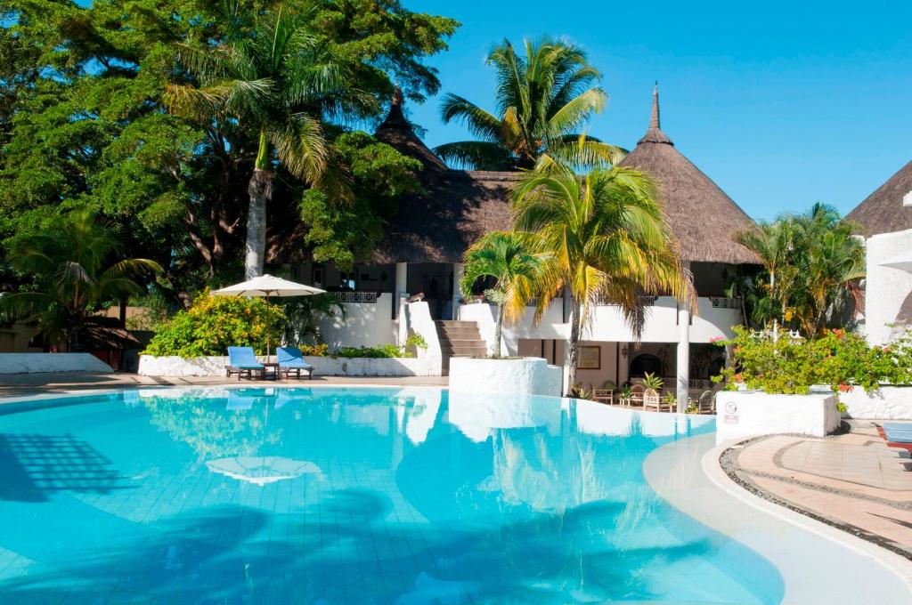 a swimming pool in front of a resort with palm trees at Casuarina Resort and Spa in Trou aux Biches