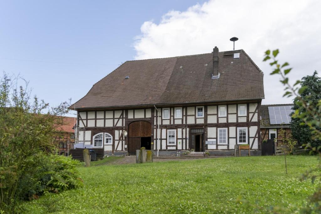 a large building with a roof on a green field at Ferienwohnung 'Im Hause Hofland' in Uslar