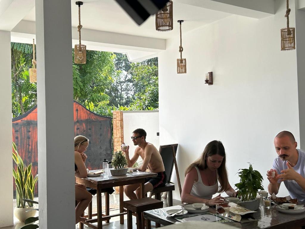 een groep mensen die aan tafels in een restaurant zitten bij Tropictide Weligama in Weligama