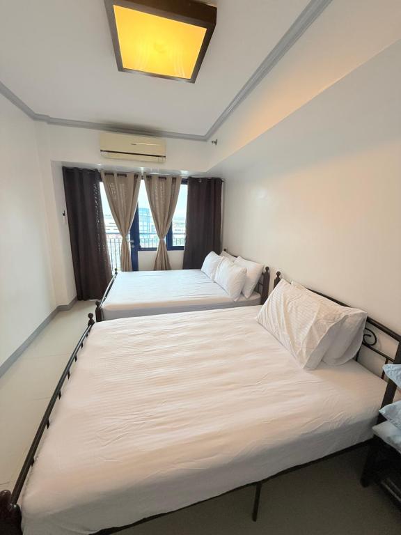 Dos camas en una habitación pequeña con ventanas. en Sea Residences at Jireh, en Pasay