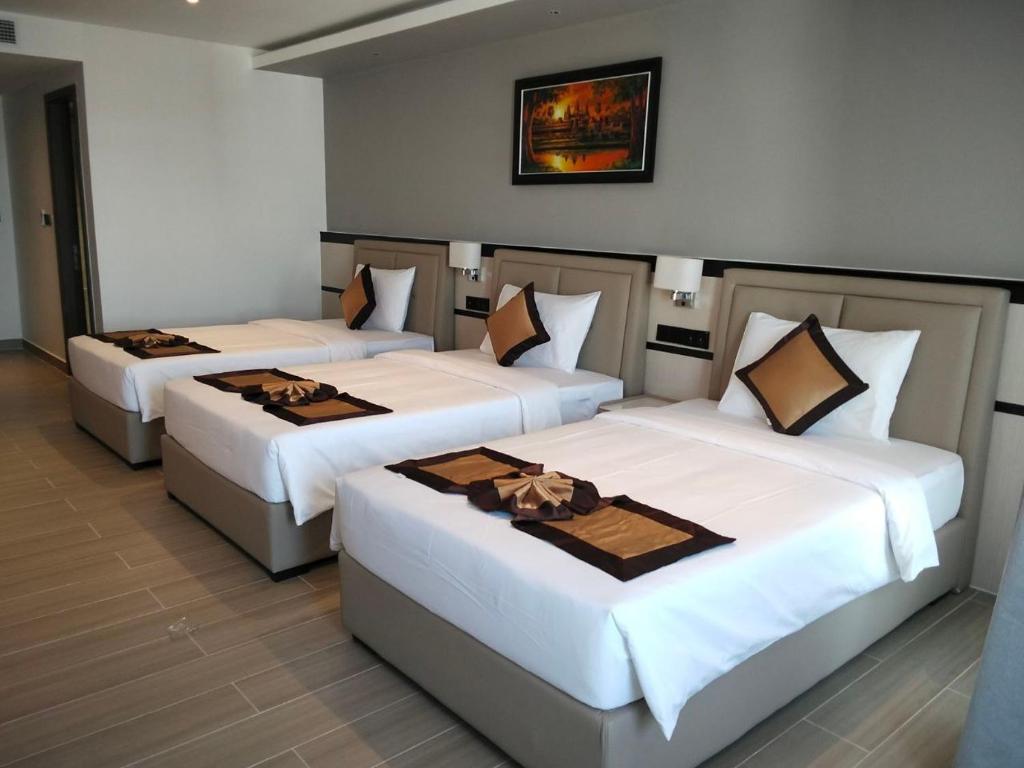 3 posti letto in una stanza con lenzuola bianche di LN hotel&Residence a Phumĭ Prêk Chrey