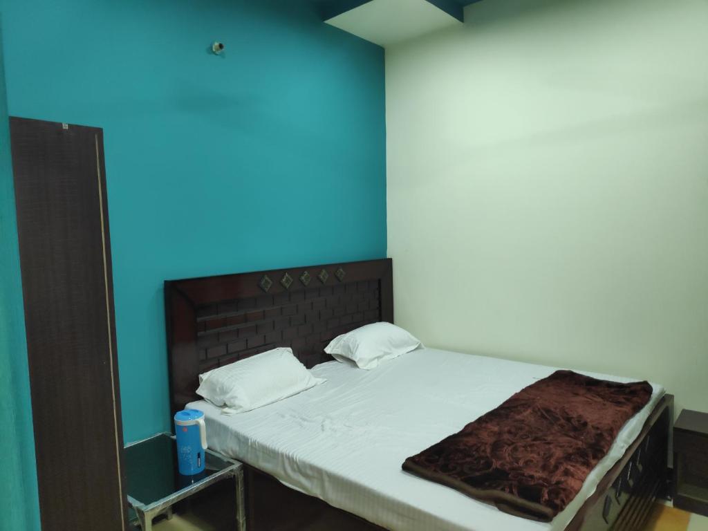 een bed in een kamer met een blauwe muur bij Sant-I Hotel in Kānpur