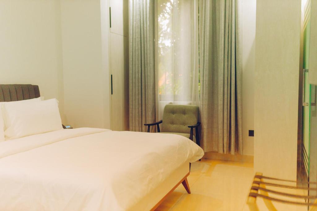 ein Schlafzimmer mit einem Bett, einem Stuhl und einem Fenster in der Unterkunft Elysium Suites & Apartments in Accra